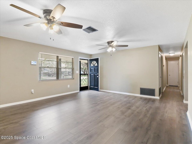 unfurnished room featuring visible vents, a textured ceiling, and wood finished floors