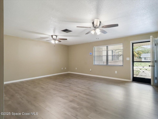 spare room with visible vents, a ceiling fan, a textured ceiling, wood finished floors, and baseboards