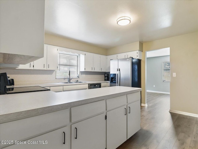 kitchen with dark wood-type flooring, a sink, baseboards, light countertops, and stainless steel refrigerator with ice dispenser
