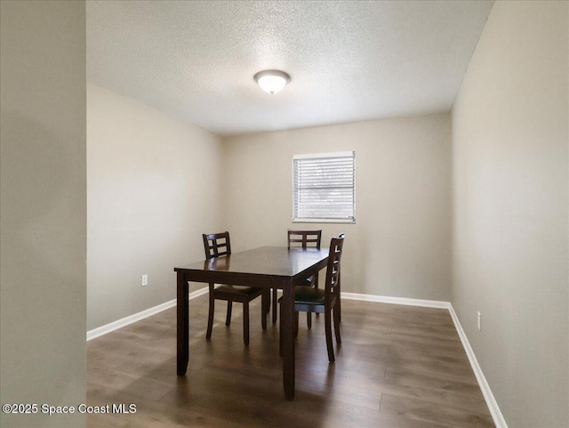 dining area featuring a textured ceiling, baseboards, and wood finished floors