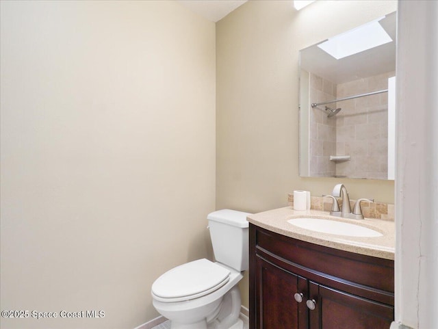 full bathroom featuring walk in shower, a skylight, vanity, and toilet