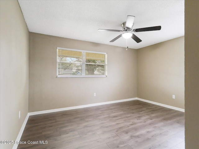 spare room with ceiling fan, a textured ceiling, baseboards, and wood finished floors