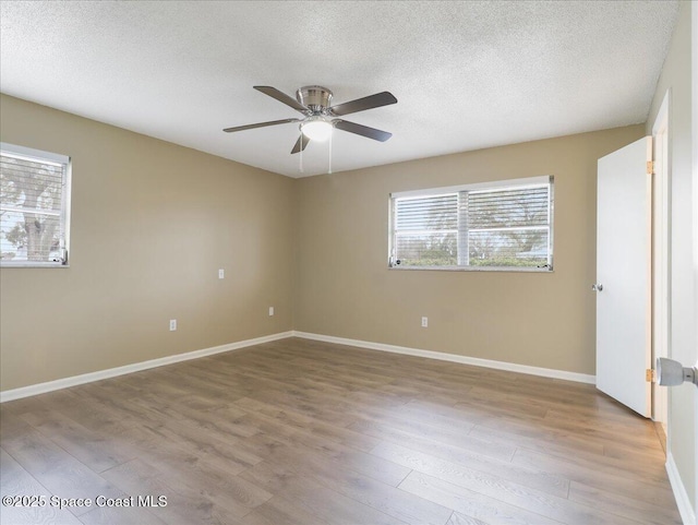 spare room with ceiling fan, a textured ceiling, baseboards, and wood finished floors