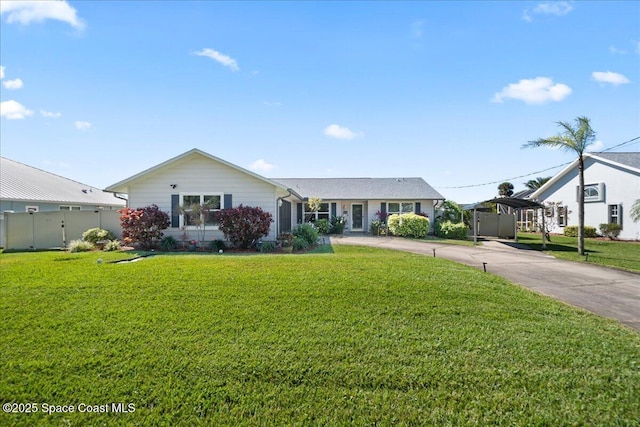 ranch-style home featuring driveway, fence, a front lawn, and a carport