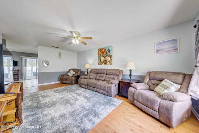 living room with ceiling fan, light wood finished floors, a textured ceiling, and visible vents