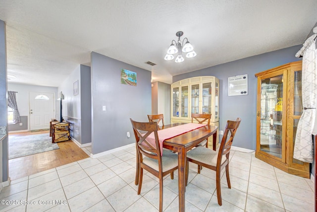 dining room with light tile patterned floors, baseboards, visible vents, and an inviting chandelier