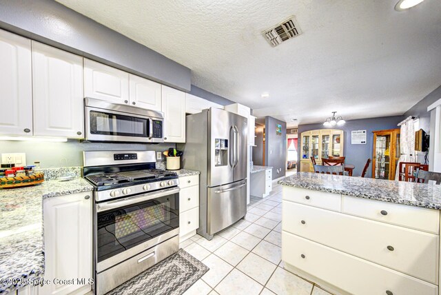 kitchen with light tile patterned floors, visible vents, appliances with stainless steel finishes, white cabinets, and a textured ceiling