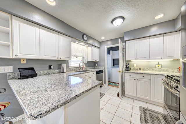 kitchen featuring appliances with stainless steel finishes, washer / clothes dryer, white cabinets, and a sink