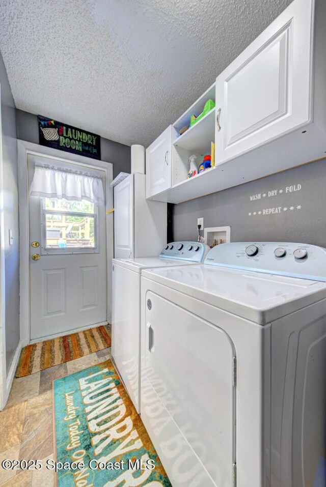 clothes washing area with a textured ceiling, cabinet space, and washer and dryer