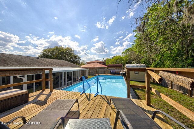 outdoor pool with an outbuilding, a shed, a fenced backyard, and a wooden deck