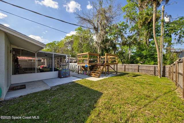 view of yard featuring a sunroom, a fenced backyard, and a patio