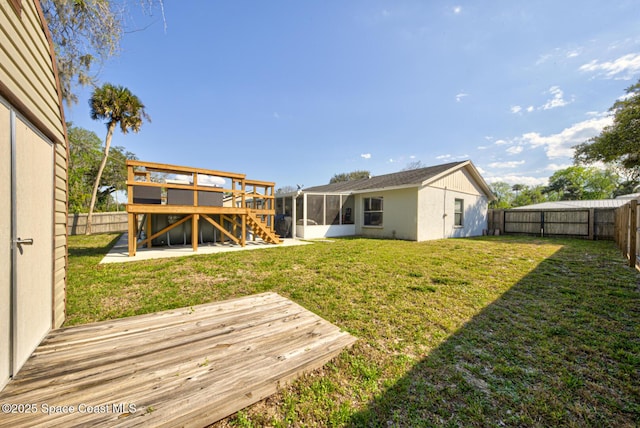 view of yard with stairway, a sunroom, a fenced backyard, and a deck