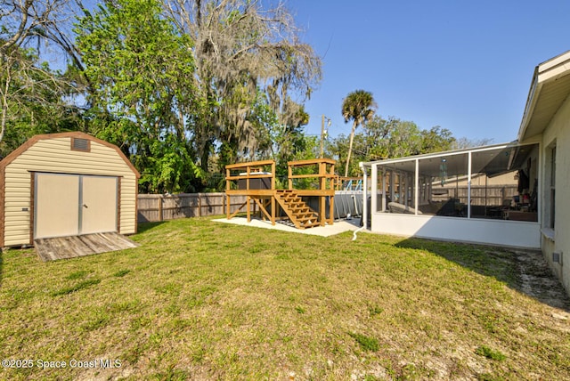 view of yard with a sunroom, a fenced backyard, an outbuilding, a wooden deck, and a shed