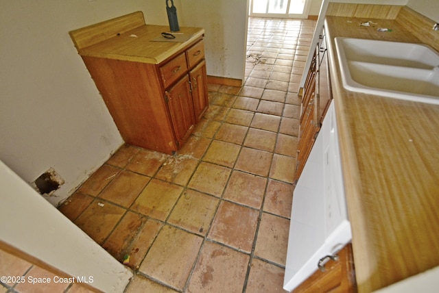 kitchen with tile patterned flooring, brown cabinetry, and a sink