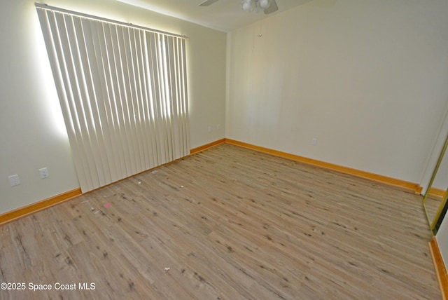 empty room featuring baseboards, a ceiling fan, and wood finished floors