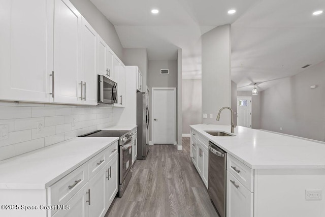 kitchen with tasteful backsplash, visible vents, appliances with stainless steel finishes, a sink, and light wood-type flooring