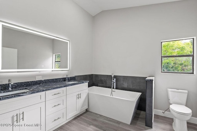 full bath with toilet, a soaking tub, lofted ceiling, wood finished floors, and a sink