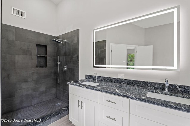 full bathroom featuring double vanity, visible vents, a sink, and tiled shower