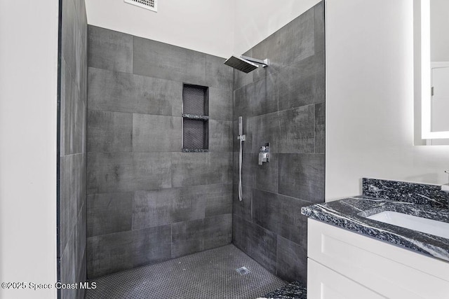 full bath with tiled shower and vanity