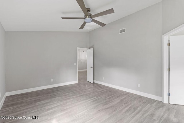 spare room with ceiling fan, wood finished floors, visible vents, baseboards, and vaulted ceiling