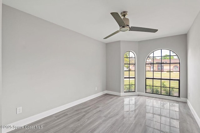 spare room with light wood finished floors, ceiling fan, and baseboards