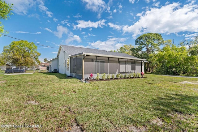 rear view of property featuring a sunroom, a yard, and fence