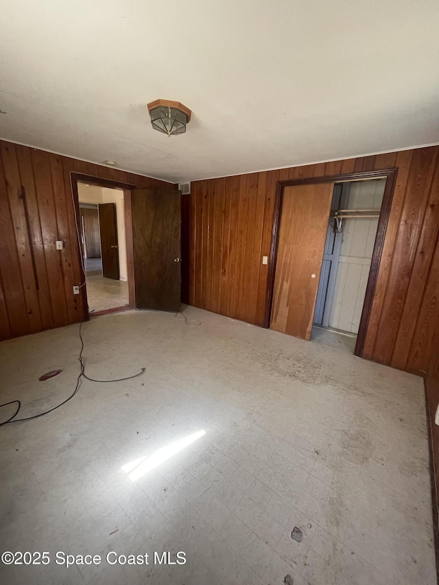 unfurnished bedroom featuring wood walls, two closets, and tile patterned floors