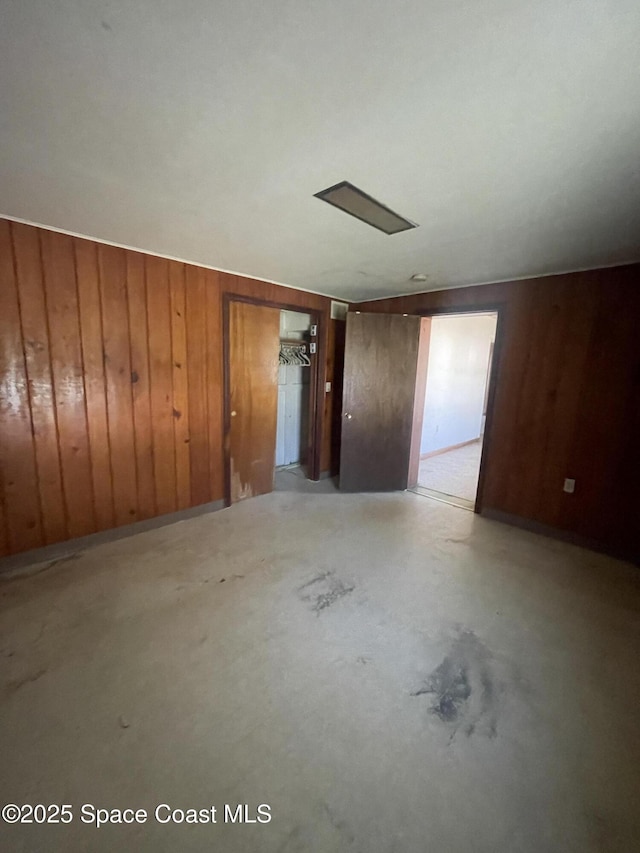 empty room featuring concrete flooring and wooden walls