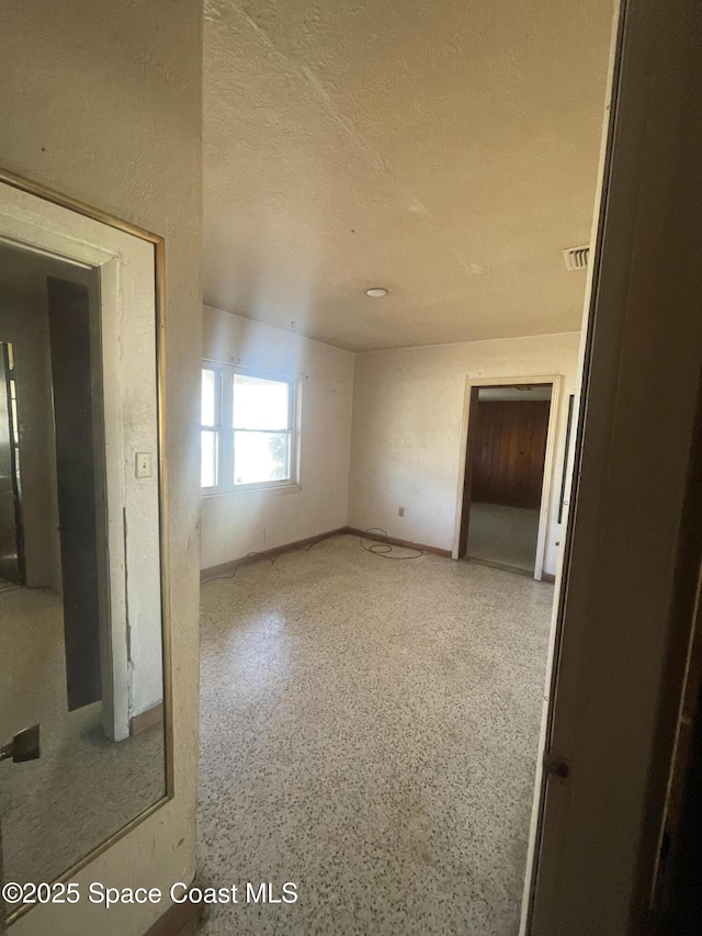 spare room with visible vents, a textured ceiling, and speckled floor