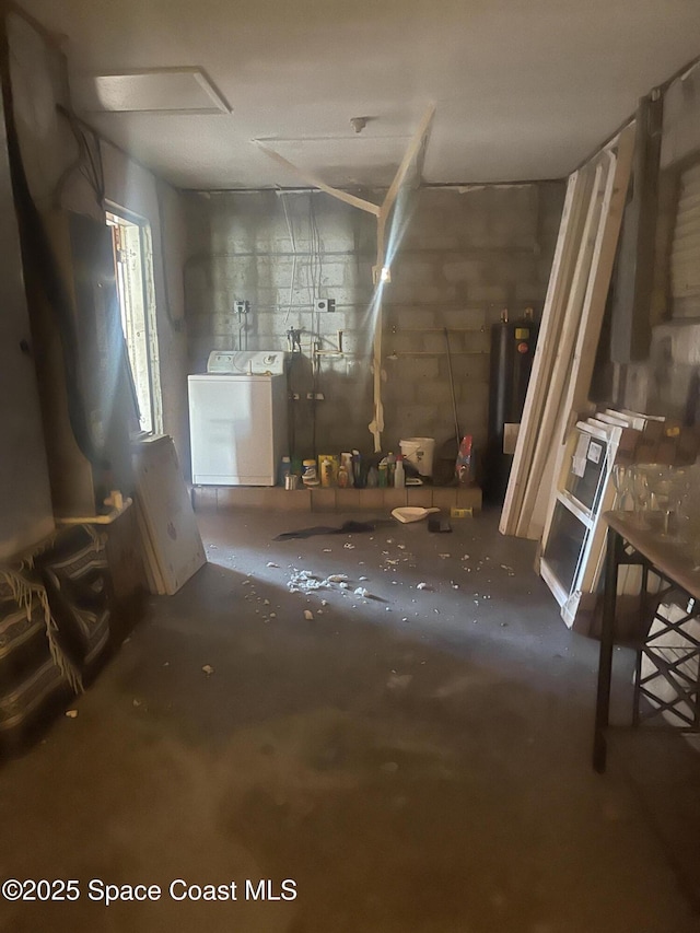 interior space featuring water heater, washing machine and clothes dryer, and concrete block wall