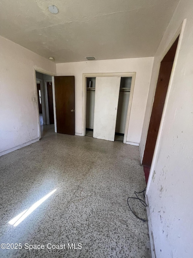 unfurnished bedroom with visible vents, a closet, and speckled floor