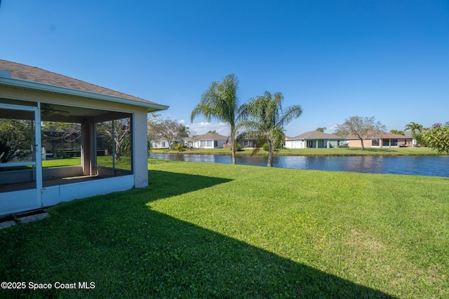 view of yard featuring a residential view, a sunroom, and a water view