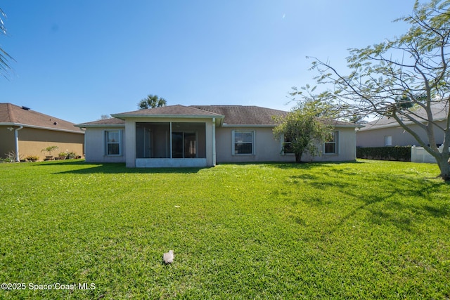 back of property featuring a lawn, a sunroom, and stucco siding