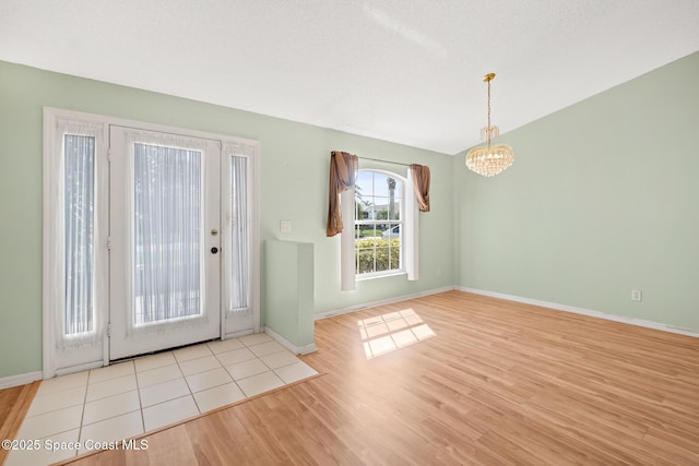 interior space with an inviting chandelier, a textured ceiling, baseboards, and wood finished floors