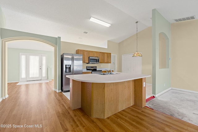 kitchen with visible vents, vaulted ceiling, stainless steel appliances, light countertops, and a sink