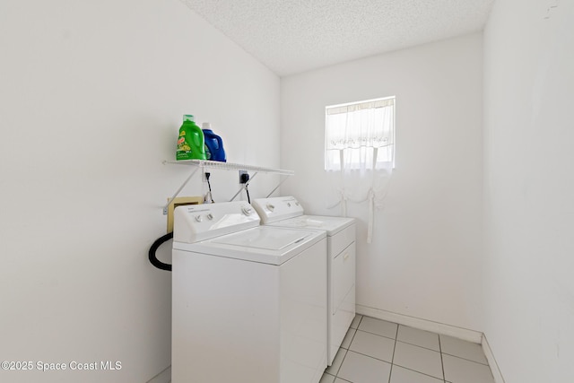 laundry room featuring a textured ceiling, light tile patterned flooring, washing machine and dryer, laundry area, and baseboards