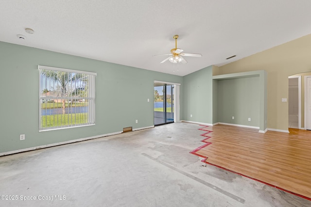 spare room with unfinished concrete flooring, visible vents, a ceiling fan, vaulted ceiling, and baseboards