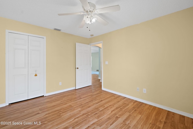 unfurnished bedroom featuring light wood-style flooring, a ceiling fan, visible vents, baseboards, and a closet