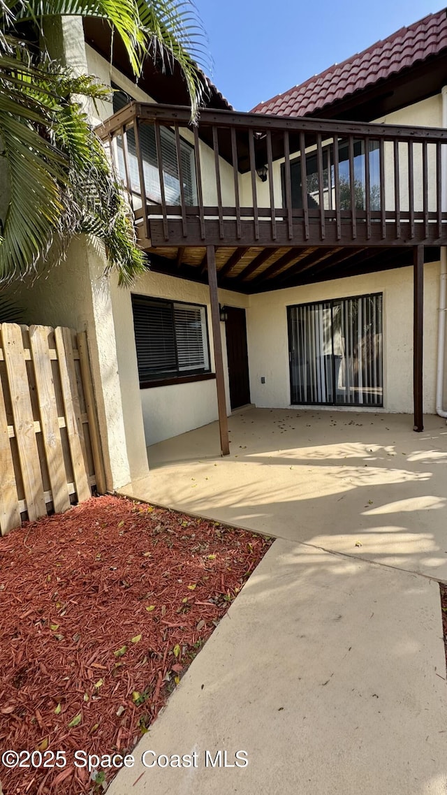 exterior space with stucco siding, a tile roof, and a patio