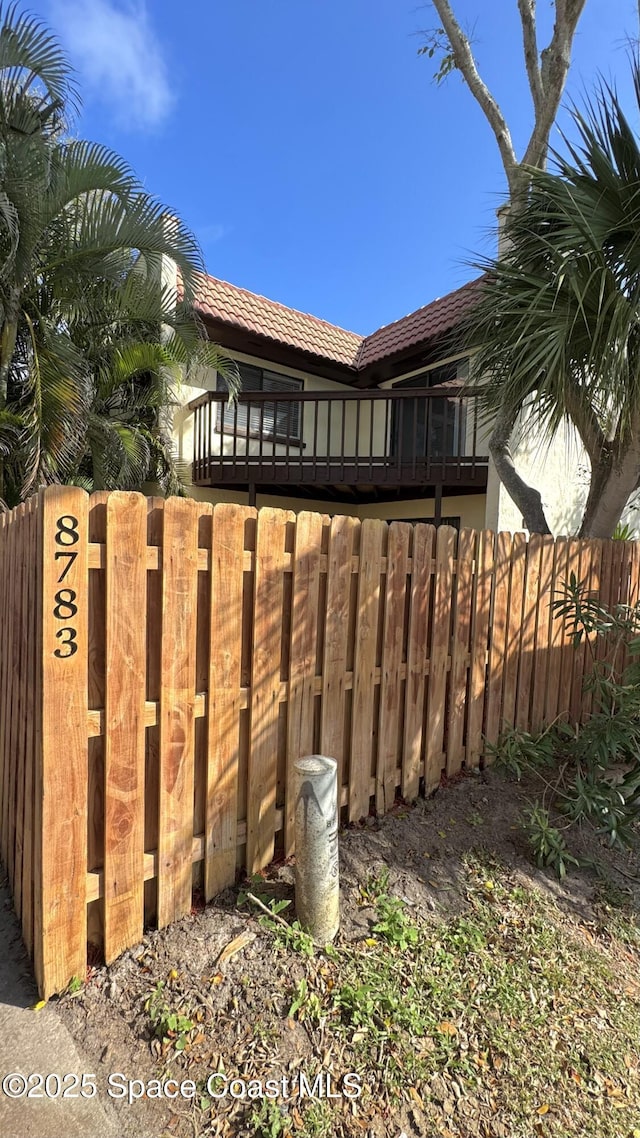 view of home's exterior featuring fence and a tiled roof