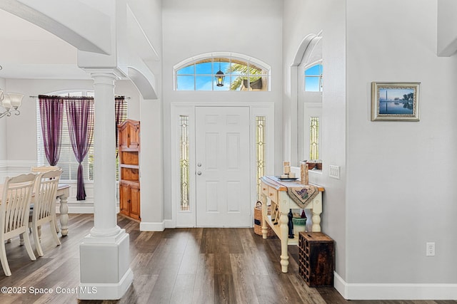 entryway featuring a chandelier, arched walkways, dark wood-style flooring, and ornate columns