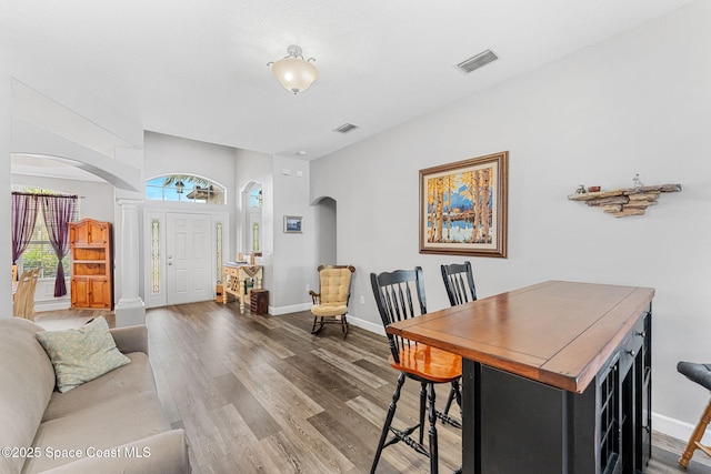 dining room with visible vents, arched walkways, and wood finished floors