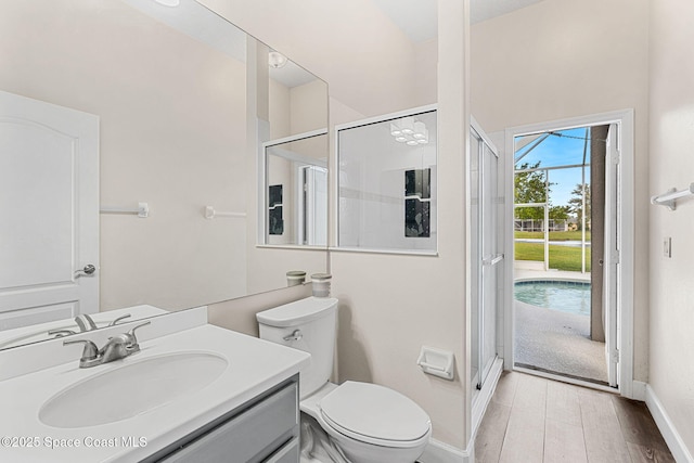 bathroom featuring baseboards, toilet, wood finished floors, vanity, and a shower stall