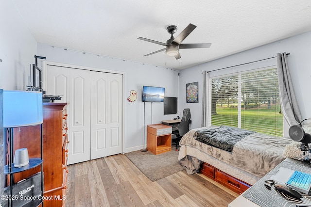 bedroom featuring light wood-type flooring, ceiling fan, a textured ceiling, and a closet