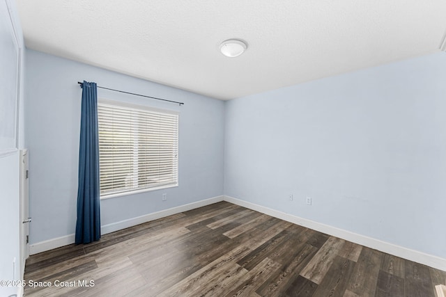 unfurnished room with dark wood-style floors, a textured ceiling, and baseboards