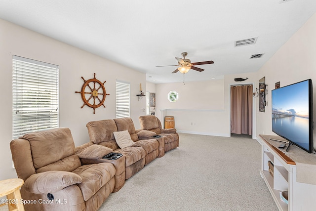 living room featuring plenty of natural light, visible vents, ceiling fan, and light colored carpet