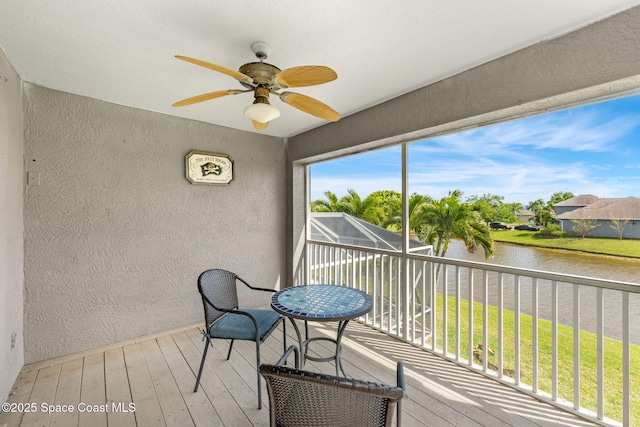 sunroom / solarium with ceiling fan and a water view