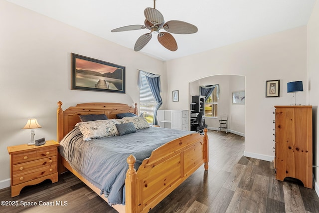 bedroom featuring baseboards, arched walkways, ceiling fan, and wood finished floors