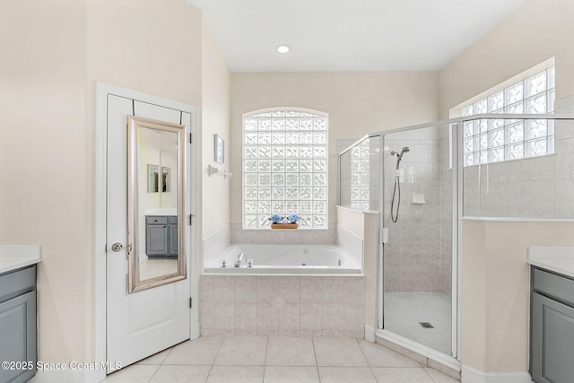 bathroom with a stall shower, tile patterned flooring, vanity, and a bath