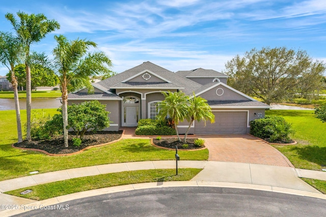 view of front of house featuring a garage, decorative driveway, a front yard, and stucco siding